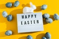 Blue textured painted Easter eggs, white plastic bunny and a luminous decorative board with the letters Happy Easter on Royalty Free Stock Photo