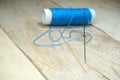 Blue threads and sewing needles on the wooden table. Royalty Free Stock Photo