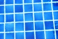 The blue tiles floor under the clear water in the swimming pool background. Royalty Free Stock Photo