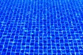 The blue tiles floor under the clear water in the swimming pool background, Swimming pool surface with floor mosaic tiles in blue Royalty Free Stock Photo