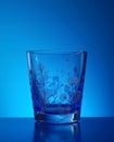 Blue toned glass with subtle botanical ornament placed inside cool atmospheric studio lighting Royalty Free Stock Photo