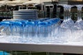 Blue tinted tumblers and wine glasses with plates stacked in a r