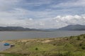 Blue Tomine reservoir with green grass, mountains at backgroudn and blue cloudy sky at sunny morning Royalty Free Stock Photo