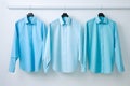 blue tone color Three men\'s long-sleeved shirts, blue tones, hanging on the wall, white background, Generated AI Royalty Free Stock Photo