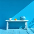 Blue-toned still life with white mug, orange fruit, and blue pot on a white table against a Royalty Free Stock Photo