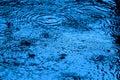 Blue toned water surface ripples and splashes in the falling rain Royalty Free Stock Photo