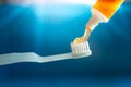 A small blue toothbrush with orange toothpaste gel on blue background Royalty Free Stock Photo