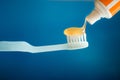 A blue toothbrush with orange toothpaste gel on blue background Royalty Free Stock Photo