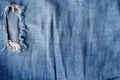 Blue torn jeans fabric texture. Distressed denim with hole and seam background Royalty Free Stock Photo