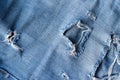 Blue torn jeans fabric texture. Distressed denim with hole and seam background Royalty Free Stock Photo