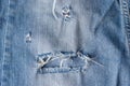 Blue torn jeans fabric texture. Distressed denim with hole and seam background Royalty Free Stock Photo