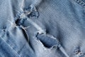 Blue torn jeans fabric texture. Distressed denim with hole and seam background Royalty Free Stock Photo