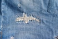 Blue torn jeans fabric texture. Distressed denim with sewn-up hole and seam background Royalty Free Stock Photo