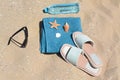 Blue towel, stylish sunglasses, slippers and bottle of water on sand. Beach accessories