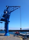 Blue tower crane in a harbor dockyard with sea and boat Royalty Free Stock Photo