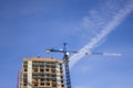 Blue tower crane near a tall building under construction on the background of a clear sky Royalty Free Stock Photo