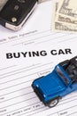 Blue toy car, key, dollar banknotes and vehicle sales agreement. Inscription buying car. Sales and buying new or used car Royalty Free Stock Photo