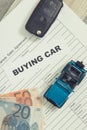 Blue toy car, key, euro banknotes and form of vehicle sales agreement. Inscription buying car. Sales and buying new or used car Royalty Free Stock Photo