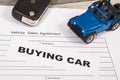 Blue toy car, key and form of vehicle sales agreement. Inscription buying car. Sales and buying new or used car Royalty Free Stock Photo