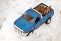 Blue toy pickup truck in winter forest on the road. Carrying fir cones in the back of a car body Royalty Free Stock Photo