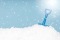 Blue toy shovel on snow with copy space on blue background Royalty Free Stock Photo