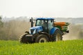 Blue Tractor and fertilizer spreader in field