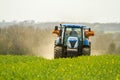 Blue Tractor and fertilizer spreader in field