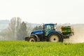 Blue Tractor and fertilizer spreader in field