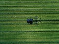 Blue tractor mowing green field, aerial view