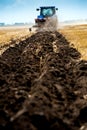 blue tractor pulls plow, tillage closeup in focus, agrarian preparing