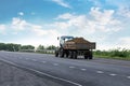 blue tractor pulls trailer with potatoes on the highway.