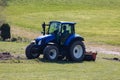 Blue tractor ready for field work but without driver on a green meadow, photographed from front side, on day without people Royalty Free Stock Photo