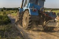 A blue tractor rides along a road in a wheat field.