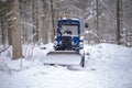 blue tractor skidded by snow, it stands in a forest strip