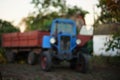 Blue tractor with trailer stands on a farm village, rural landscape Royalty Free Stock Photo