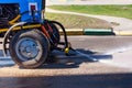 Blue tractor watering asphalt for cleaning dust and dirt.  Summer road cleaning Royalty Free Stock Photo