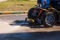 Blue tractor watering asphalt for cleaning dust and dirt.  Summer road cleaning Royalty Free Stock Photo