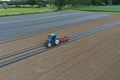 Blue tractor working on an agricultural field with evenly spaced rows prepared for planting. Royalty Free Stock Photo