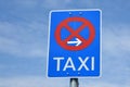 Blue traffic sigh with red crossed circle, arrow pointing to the right and word `Taxi` written on it