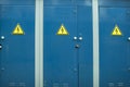 Blue transformer box.Locked electric metal door with a sign of attention on the blue wall of the transformer substation