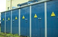 Blue transformer box.Locked electric metal door with a sign of attention on the blue wall of the transformer substation