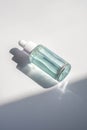 A blue transparent bottle with serum in the rays of the sun. Royalty Free Stock Photo
