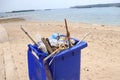 Trash bin beside the sandy beach and full of plastic waste Royalty Free Stock Photo