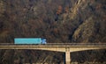 Blue truck, freight carrier, crosses the bridge over the water.