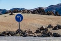 Blue turn left sign on a volcanic desert.