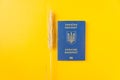 Blue Ukraine biometric passport isolated on energizing yellow color background with ear of wheat. Immigration.