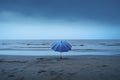 blue umbrella in a gloomy beach, AI generated