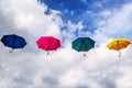 Blue Umbrella, Red Umbrella, Green Umbrella and Yellow Umbrella floating in the Air under Blue Sky and Clouds Royalty Free Stock Photo