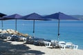 Blue umbrellas and chaise for relax and comfort on sea beach. Happy summer vacations and tourism concept. Paid service on