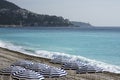 Blue umbrellas, reserved tables with white tablecloths on the pebble beach of the Promenade des Anglais in Nice, France, await gue Royalty Free Stock Photo
